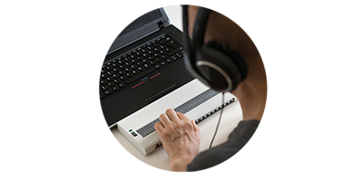 A man operates a Braille display in front of a laptop.