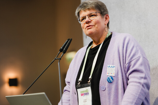 Birgit Peböck steht am Redepult des axes4 Days und spricht in die Richtmikrofone.