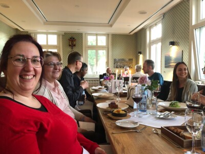 Ein Teil des Teams beim Abendessen im Hofgut Rosenau am Tisch sitzend. Marion lacht in die Kamera, die anderen unterhalten sich angeregt.