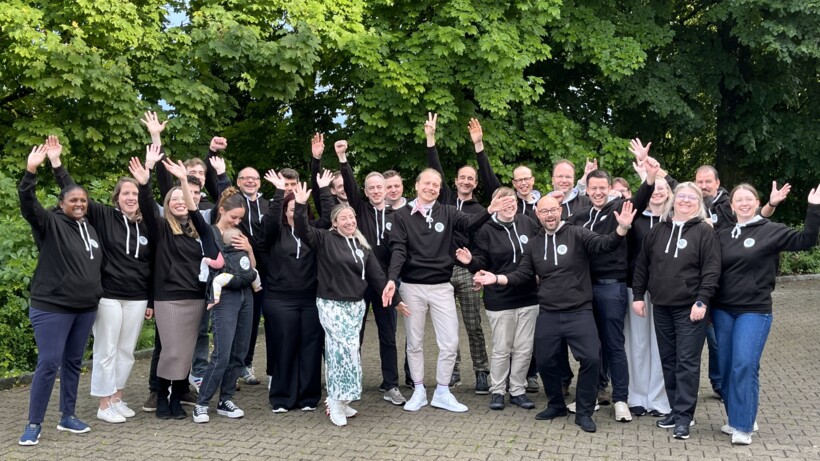 Jubelndes axes4-Team beim 10-jährigen Jubiläum. Alle tragen schwarze A11y-Champion Hoodies.