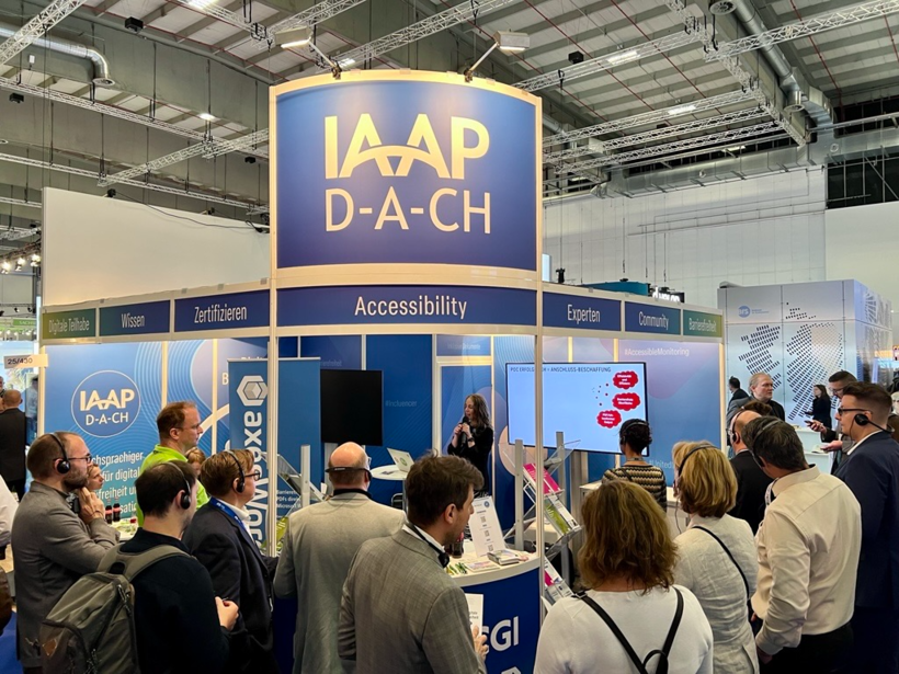 Josephine Schwebler, IT-Systemhaus der BA, hält am Gemeinschaftsstand von IAAP D-A-CH, axes4 und weiteren Mitgliedsorganisationen einen Kurzvortrag zur Einführung von axesWord bei der Bundesagentur für Arbeit. Das Publikum hat Kopfhörer auf, um dem Vortrag optimal folgen zu können.